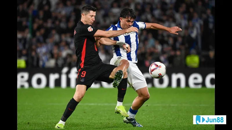 Cầu thủ Barca đi bóng qua cầu thủ của Real Sociedad trong trận đấu